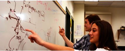 Two students analyzing a math problem in Physics.