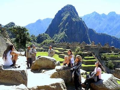 Turistas visitando Machu Picchu con montañas andinas al fondo en Perú