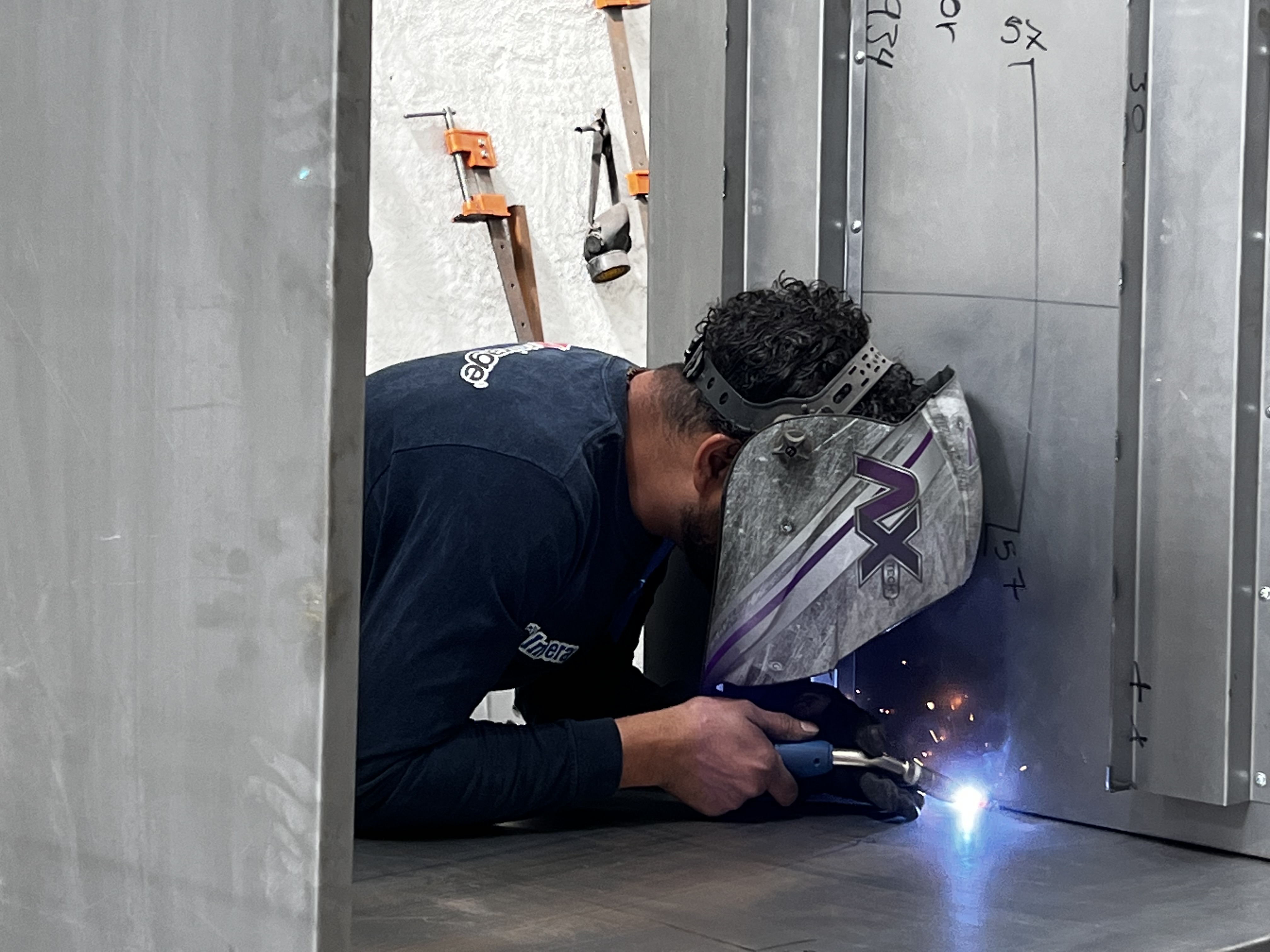 Nevera con bebidas y alimentos en oficina moderna con personas trabajando.