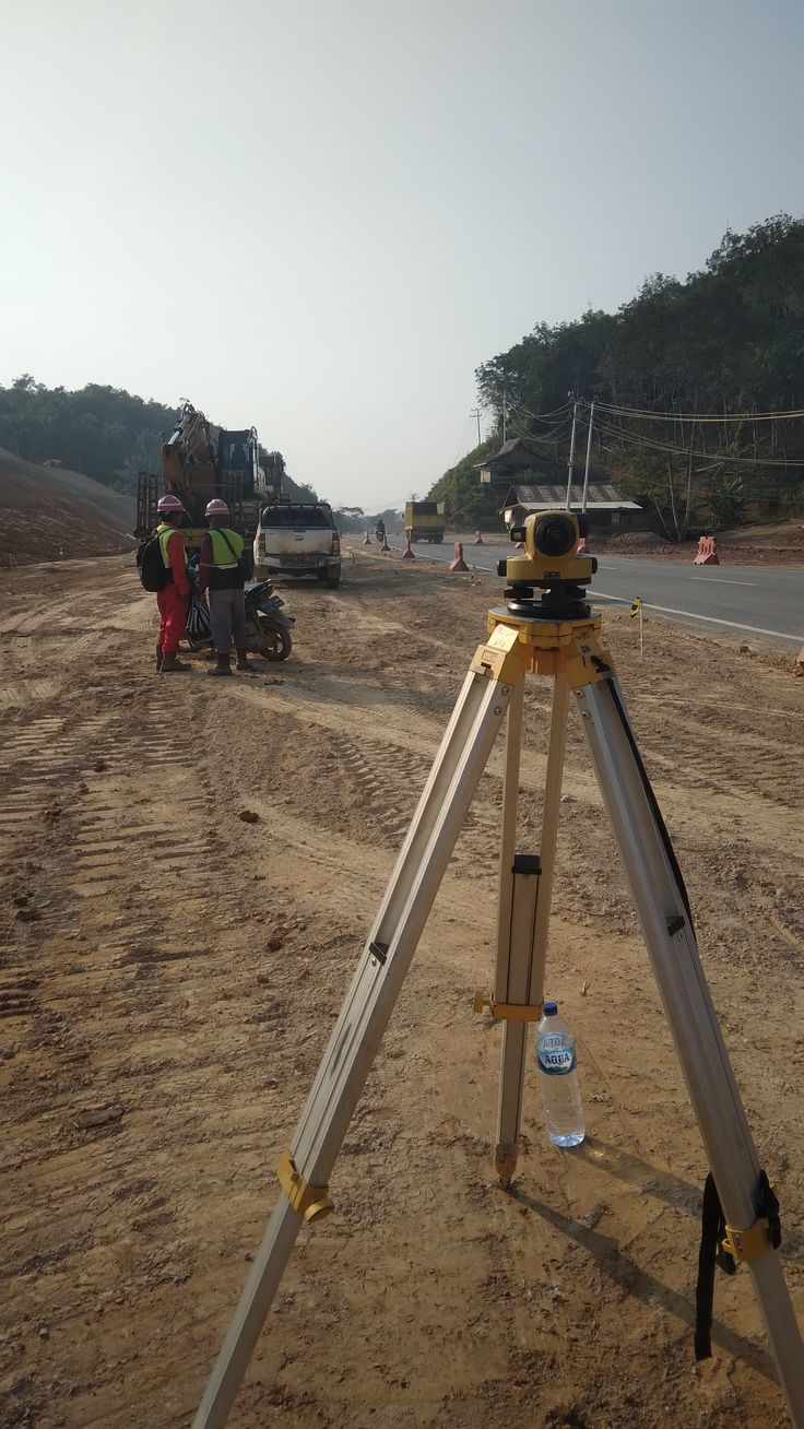 Obrero de construcción con casco junto a maquinaria pesada en obra ferroviaria urbana con grúas y rascacielos al fondo Obrero de construcción con casco junto a maquinaria pesada en obra ferroviaria urbana con grúas y rascacielos al fondo