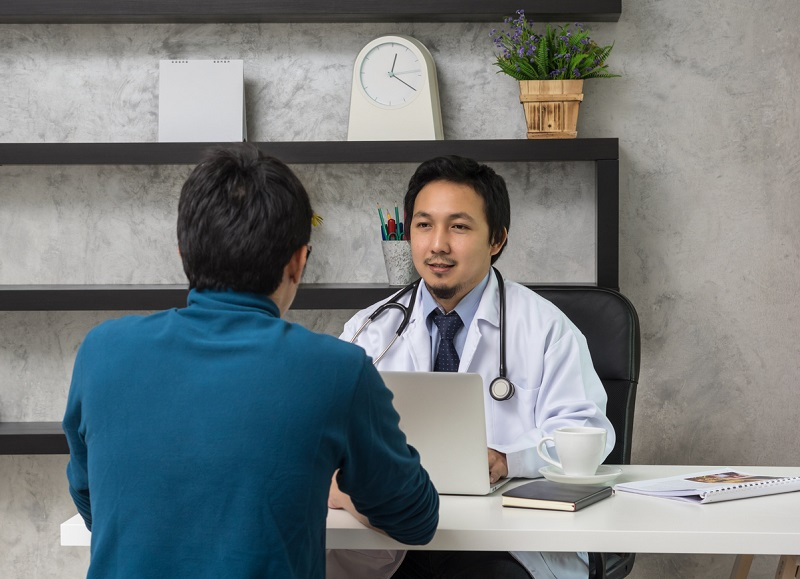 Asian male doctor discussing diagnosis with patient