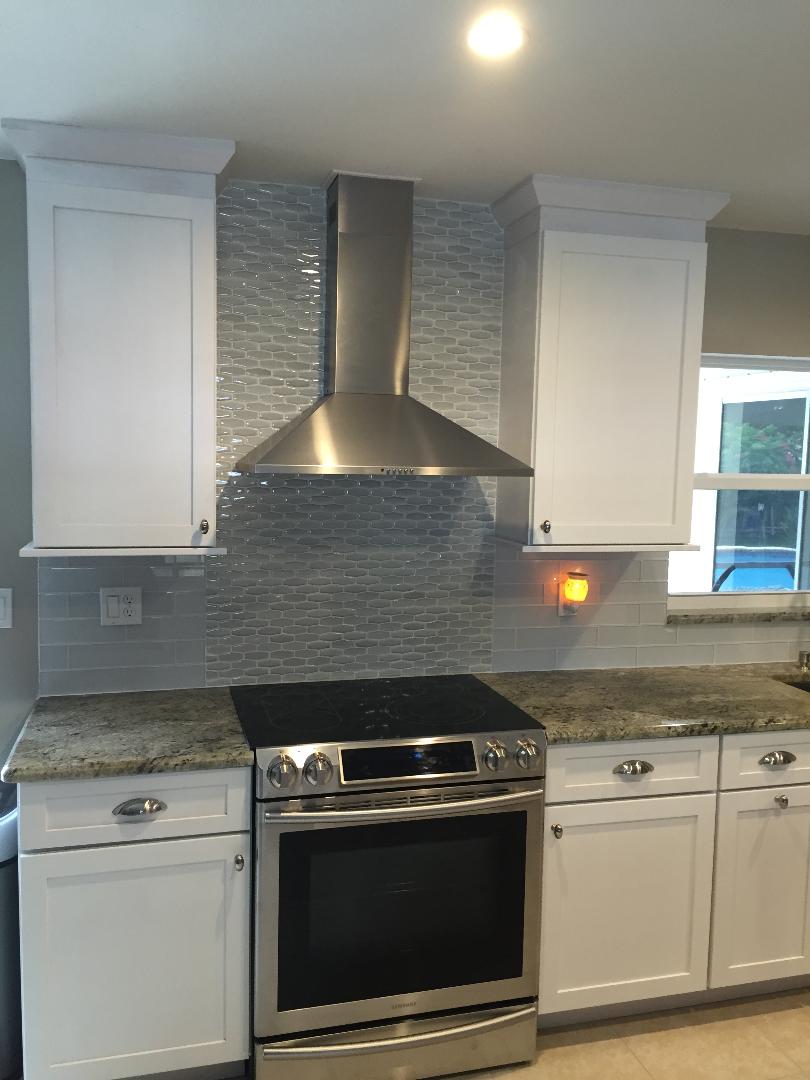 Gorgeous hood vent featuring a glossy patterned backsplash.