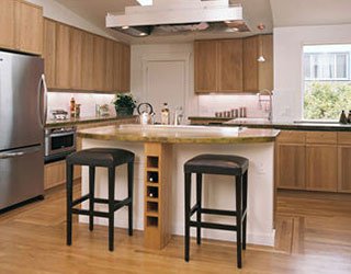 This kitchen features oak cabinets, oak floors, and a concrete island countertop which overhangs to provide bar seating. 