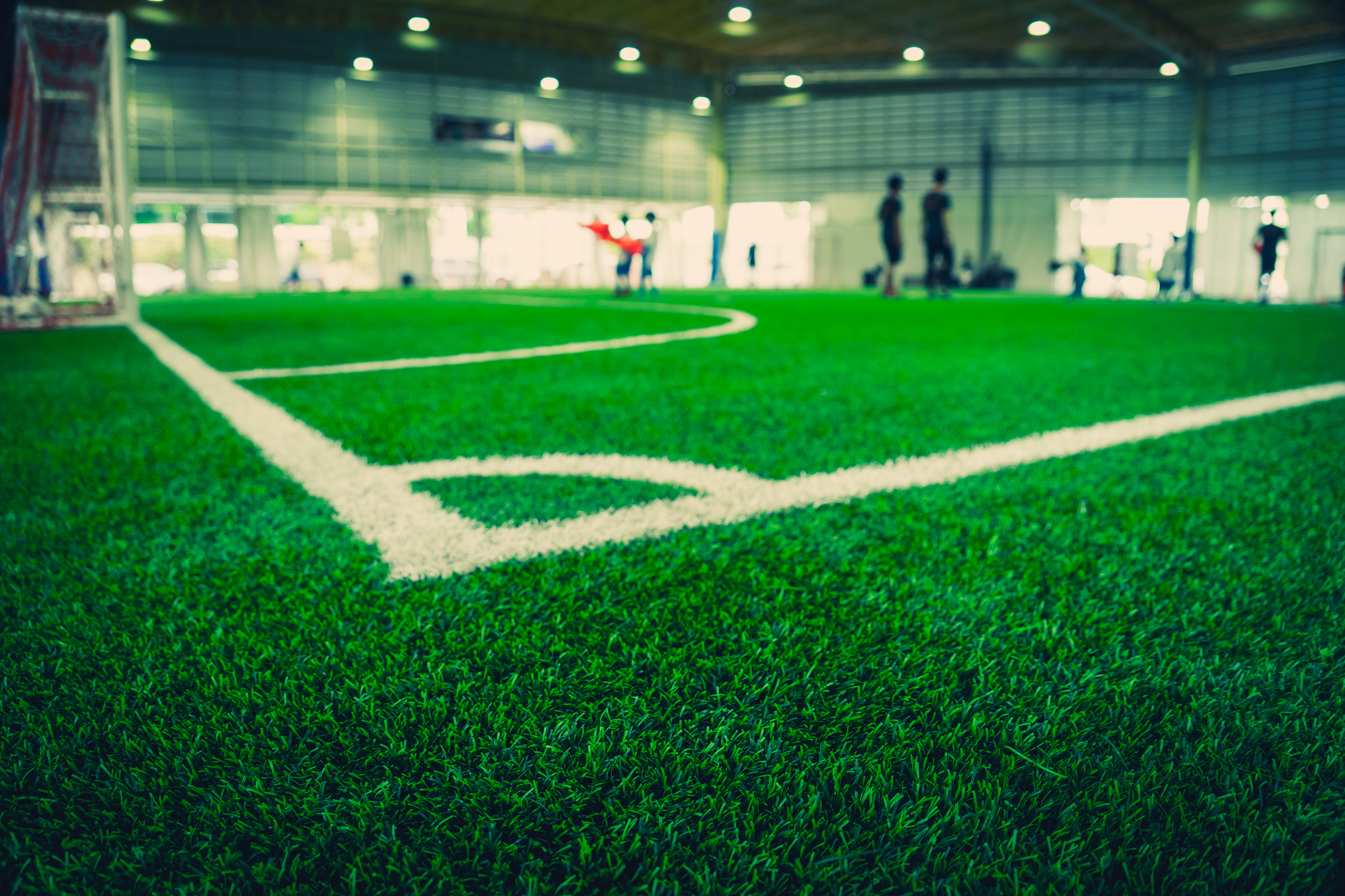 Close up of the corner of a soccer field with blurred people in the distance