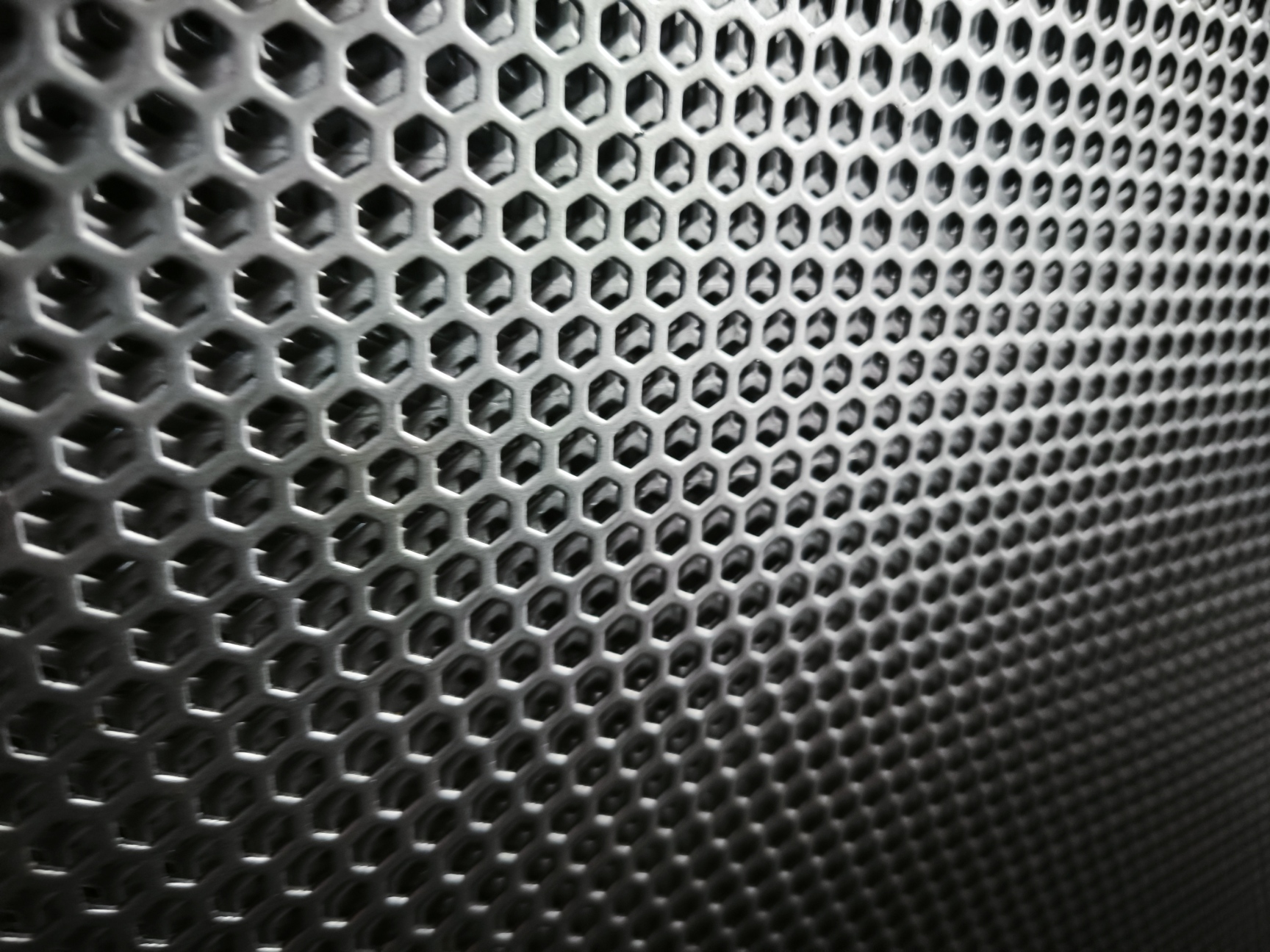 Primer plano de una rejilla metálica con patrón hexagonal.
