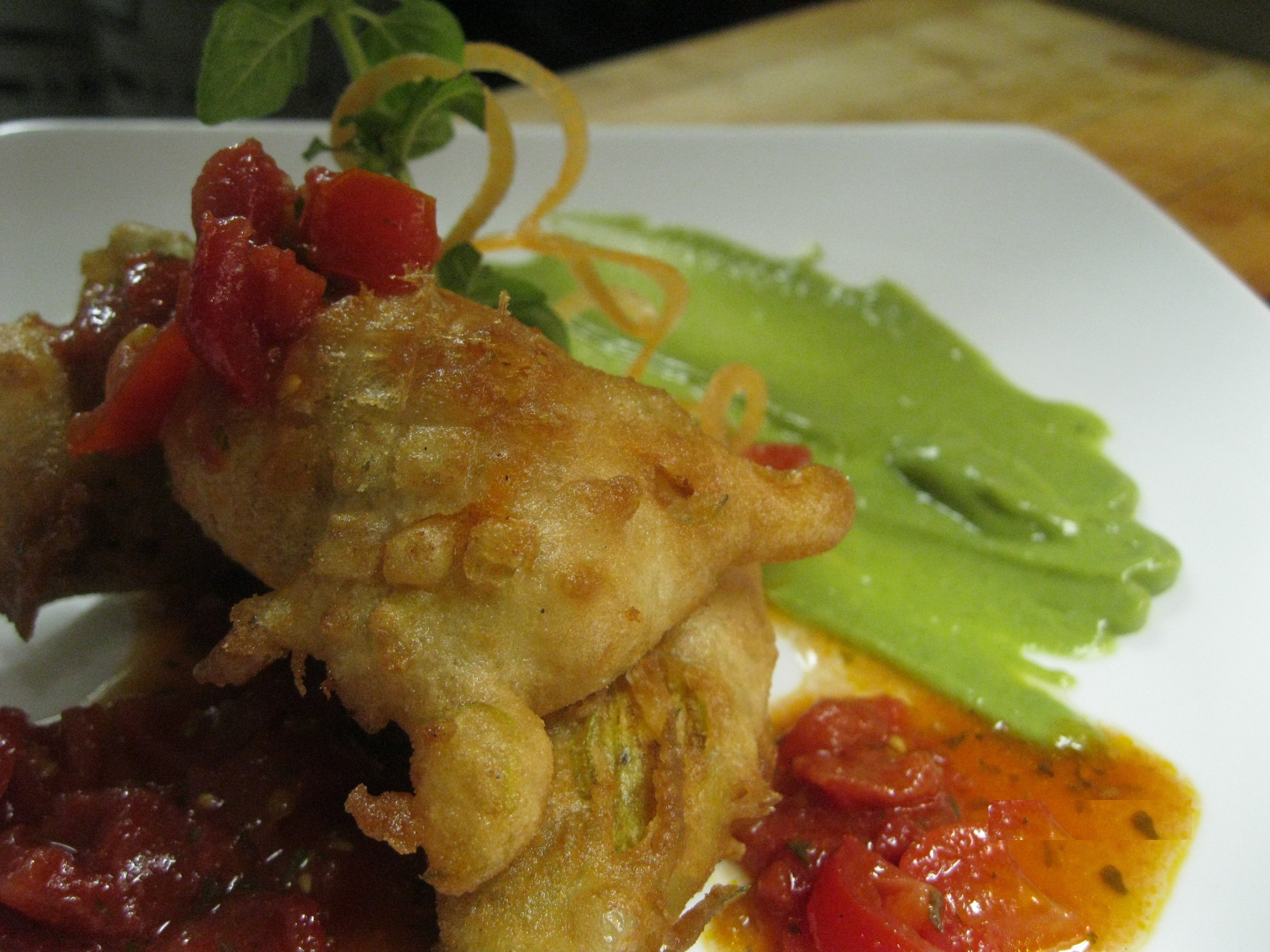 crab stuffed  zucchini blossom with an avocado coulis and heirloom tomato concasse