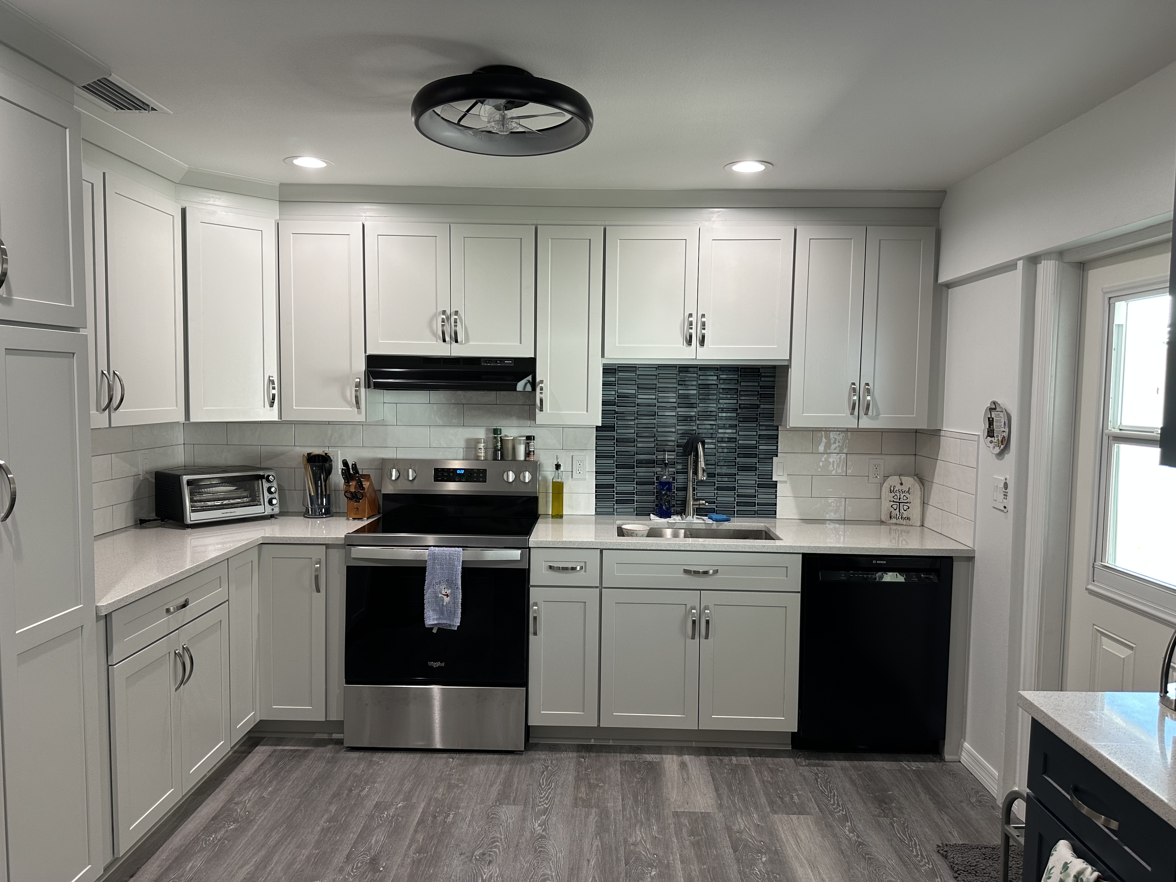 The new gray LVP flooring elevates the kitchen while allowing the blue glass backsplash behind the sink 
area and the 4x12 white tile backsplash to shine.  Making the space both beautiful and functional.