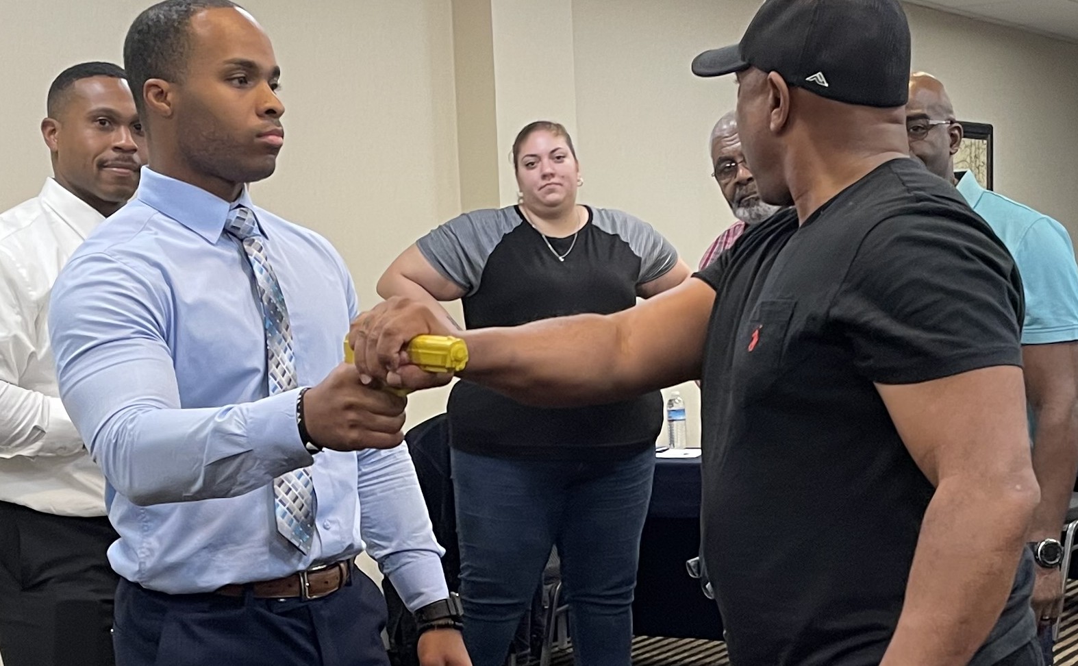 Police officer standing in office hallway with colleagues in the background. Police officer standing in office hallway with colleagues in the background.