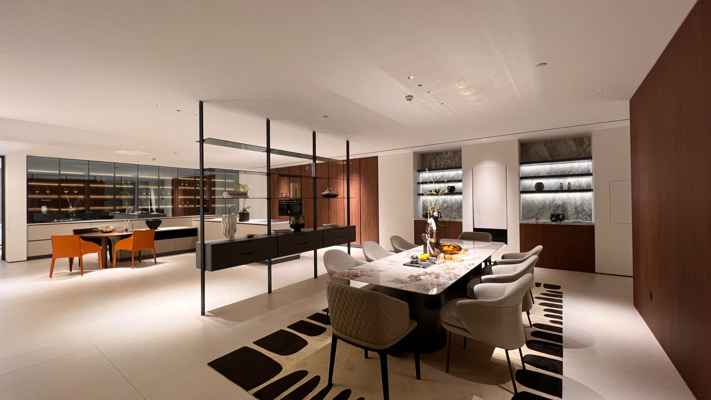 Modern open-plan living and dining room with a sectional sofa, decorative shelving, wooden dining table, and contemporary lighting. Modern open-plan living and dining room with a sectional sofa, decorative shelving, wooden dining table, and contemporary lighting.