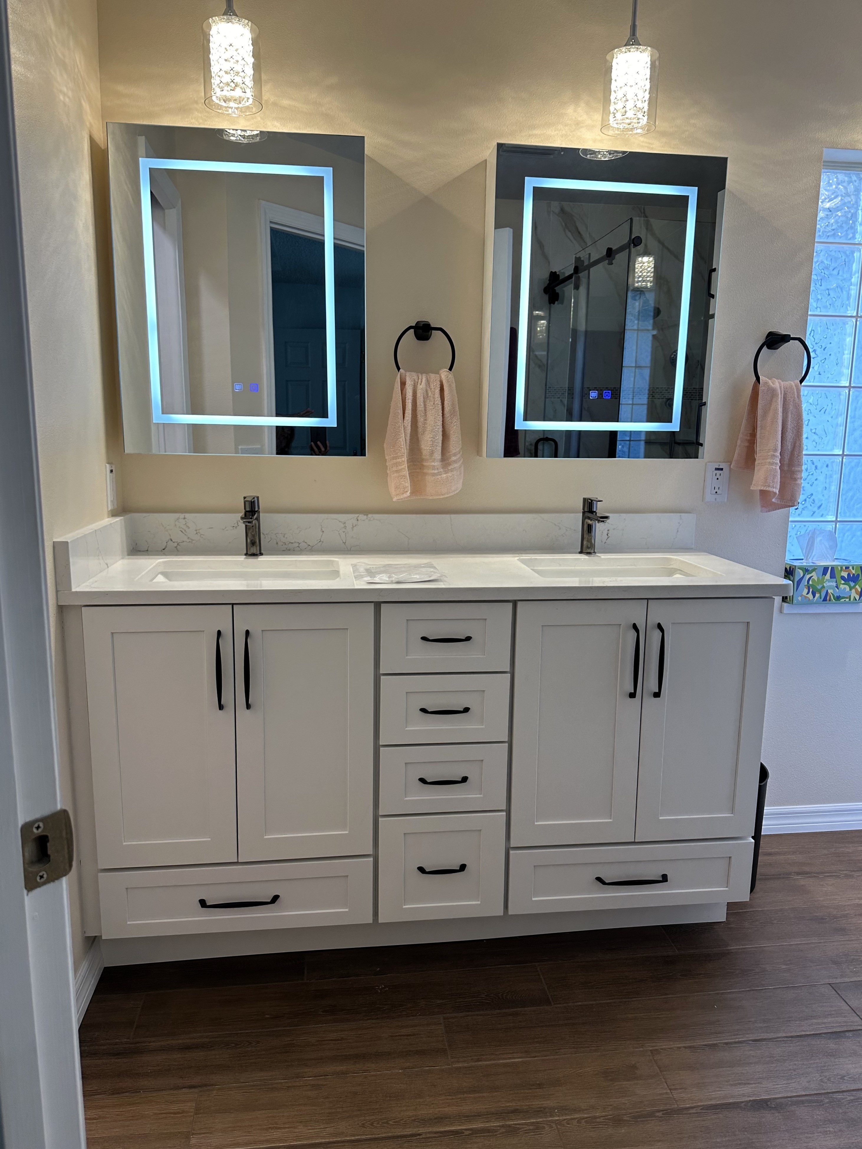 Semi-custom painted white maple cabinetry with matte black handles, Pompeii Misterio Gold quartz countertop with matching 4" backsplash, single handle faucets, and identical mirrors make this a standout vanity for two.