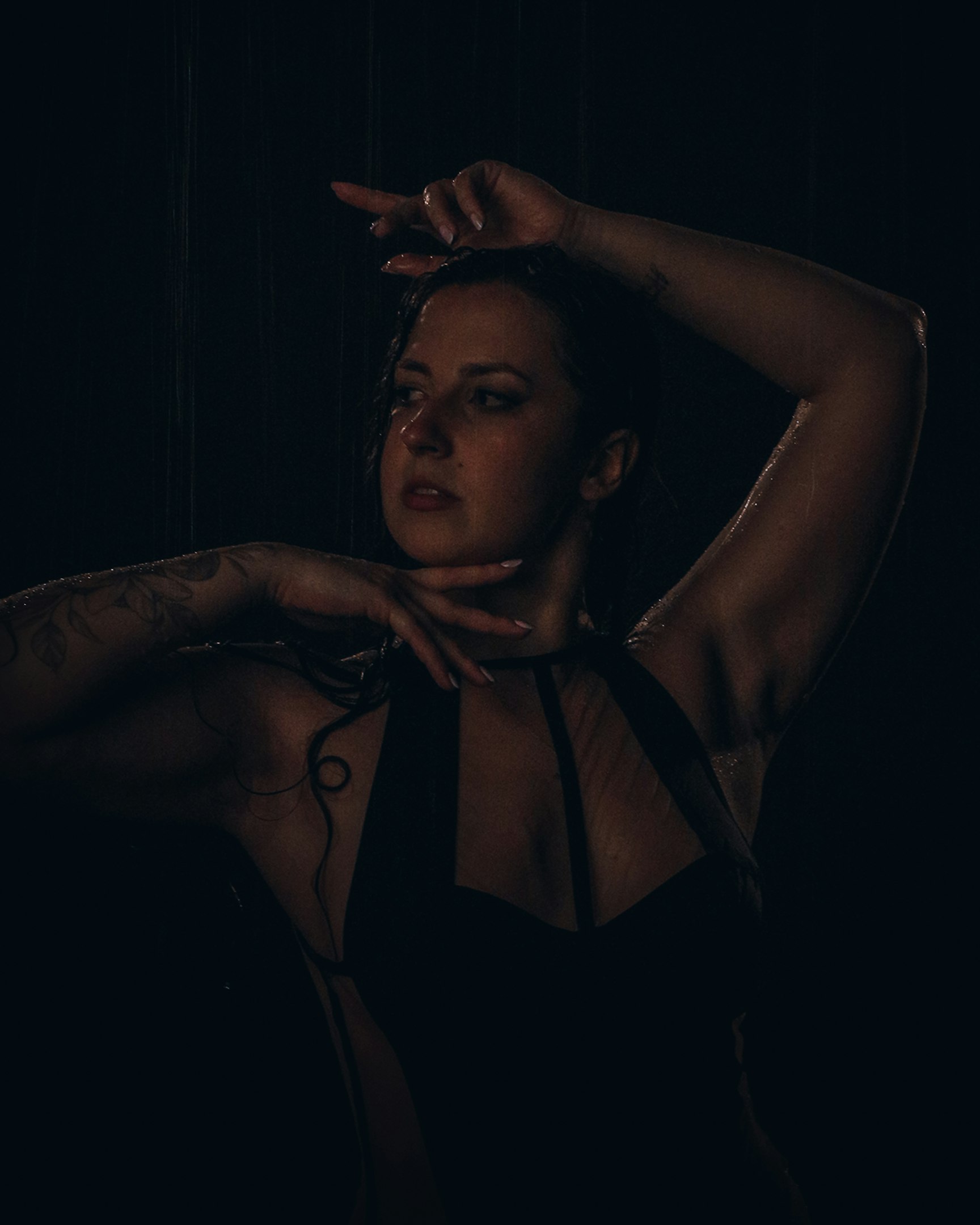 una mujer en una habitación oscura con las manos en la cabeza