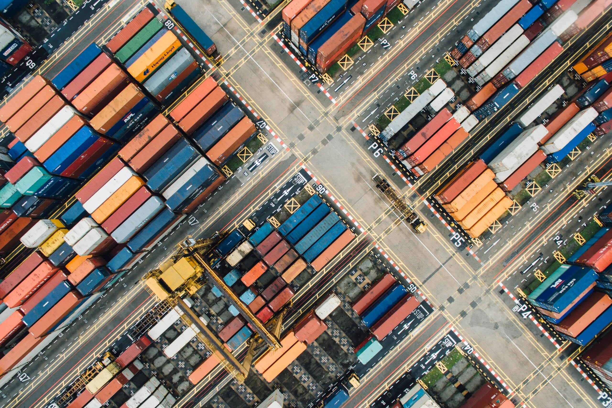 Aerial view of a busy shipping port with rows of colorful shipping containers and cranes. Aerial view of a busy shipping port with rows of colorful shipping containers and cranes.