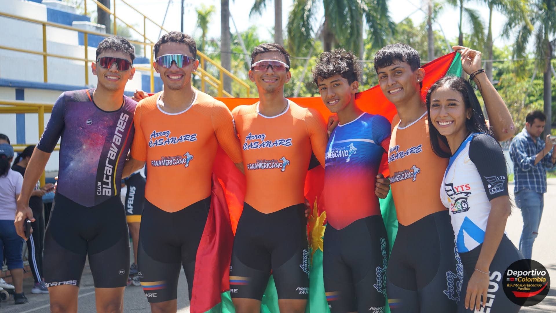 Grupo de patinadores colombianos sonrientes con uniformes deportivos y bandera en competencia al aire libre