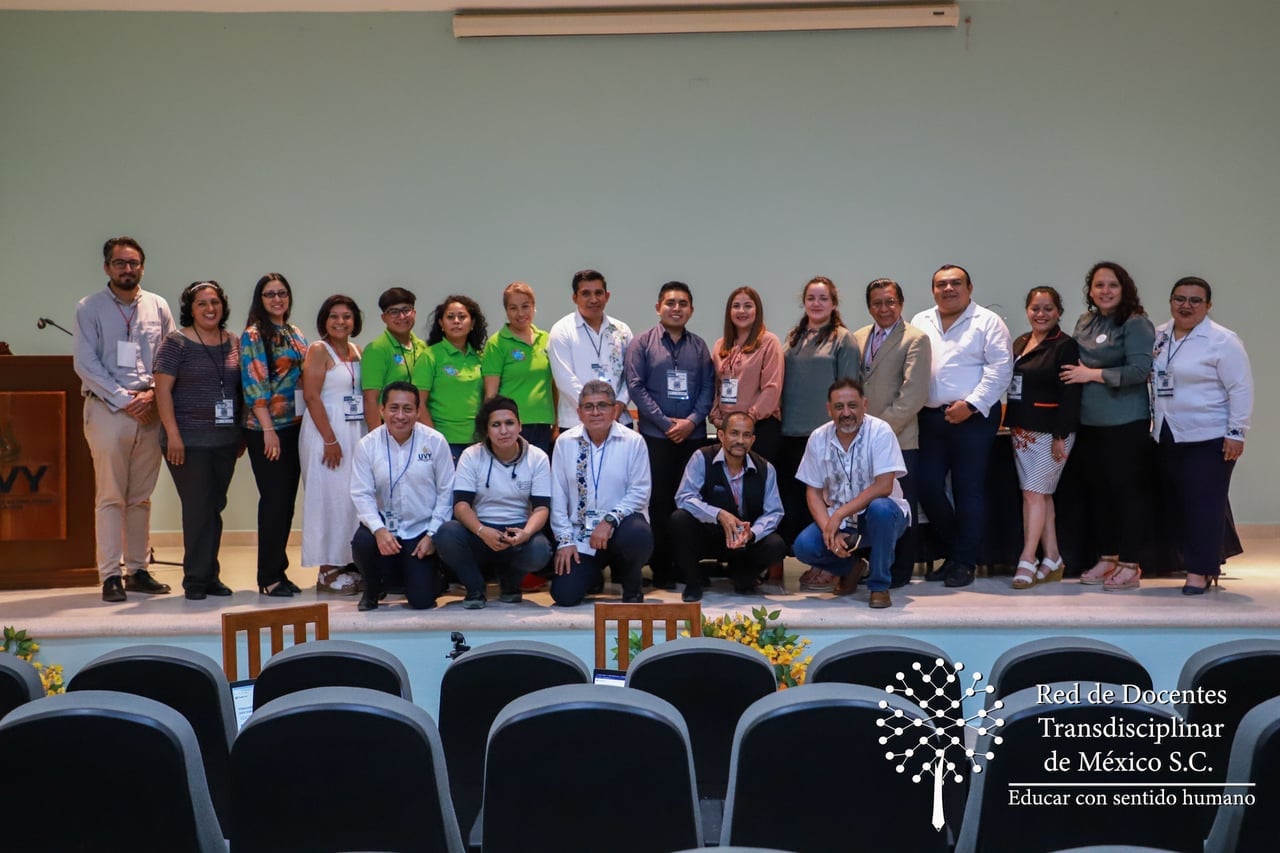 Grupo de docentes posando en un auditorio con el logo de la Red de Docentes Transdisciplinar de México.
