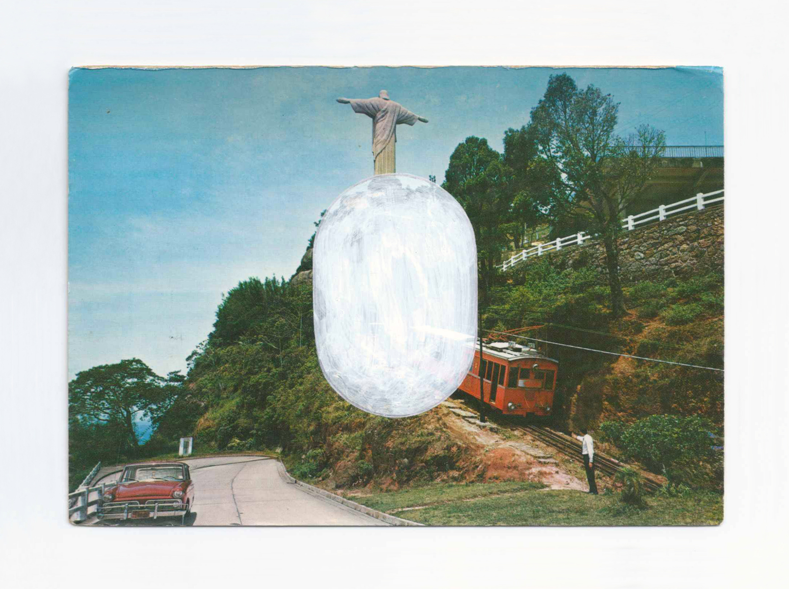 An old postcard of a car, tram, man and Christ statue, plus a white painted oval.