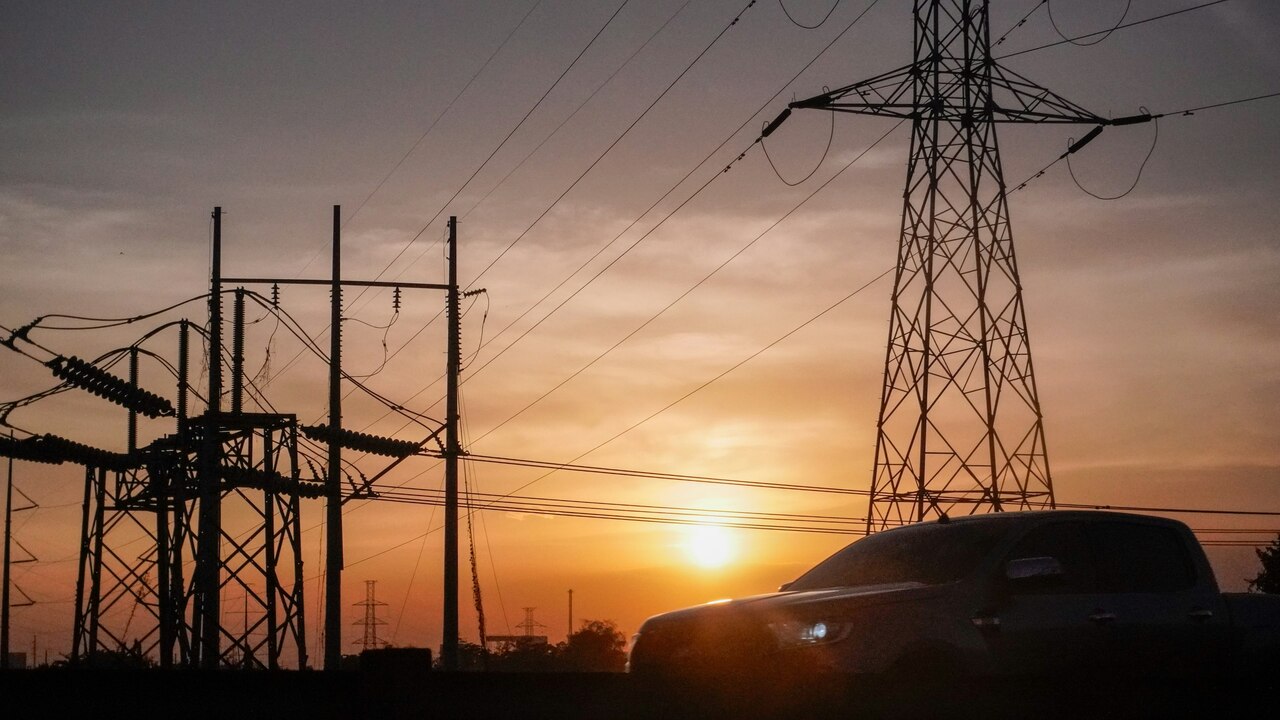 un coche está estacionado frente a las líneas eléctricas al atardecer