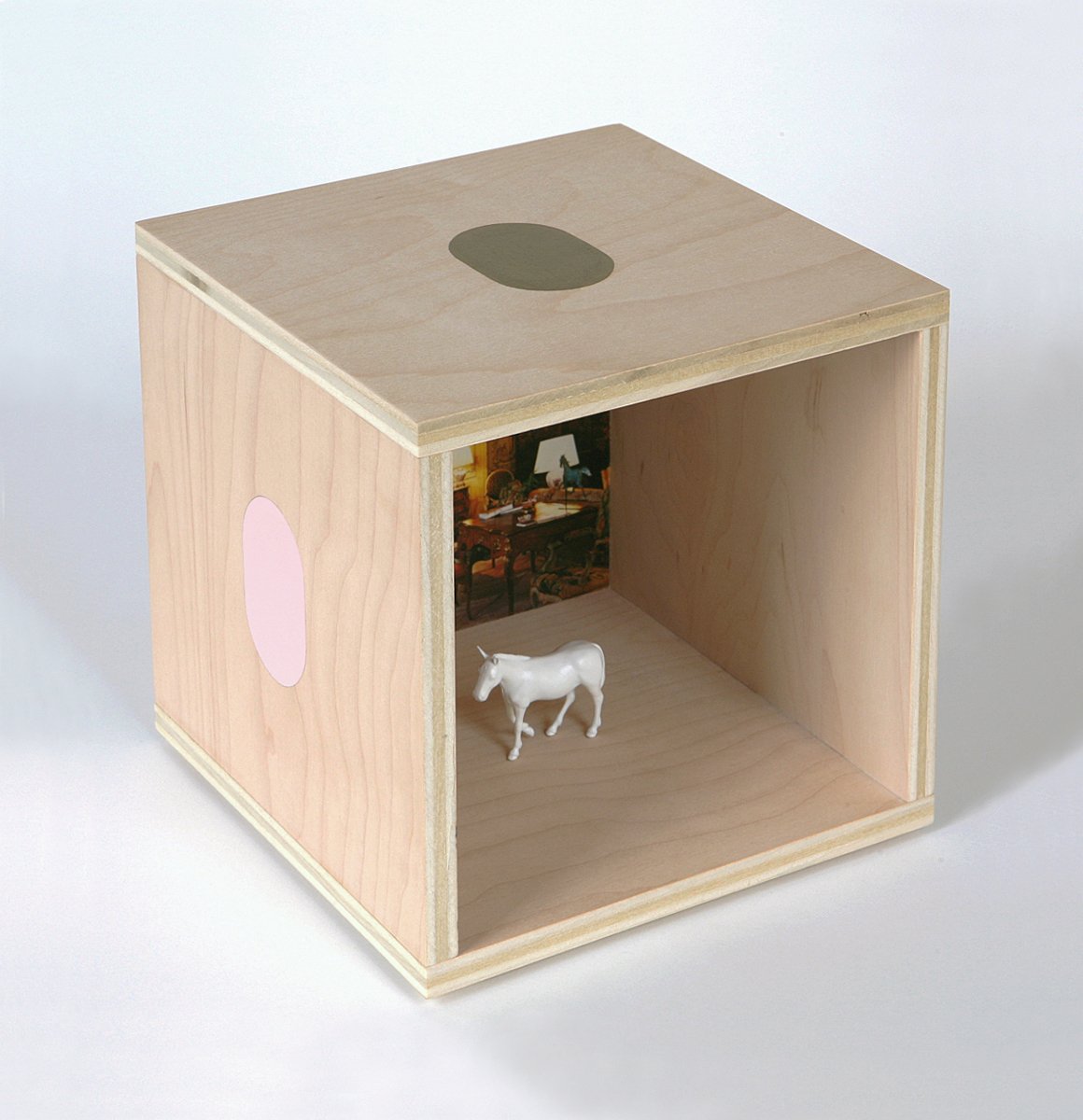 A plywood cube with ovals on the outside and a small white mule model inside.