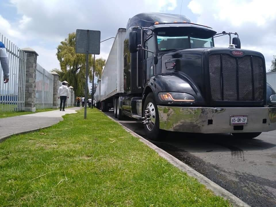 Camión negro estacionado en una calle con césped y personas caminando en la acera. Camión negro estacionado en una calle con césped y personas caminando en la acera.
