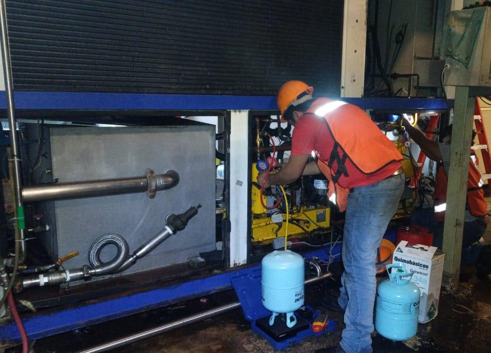 Compresores industriales azules instalados en un recinto, conectados por tuberías y cables.