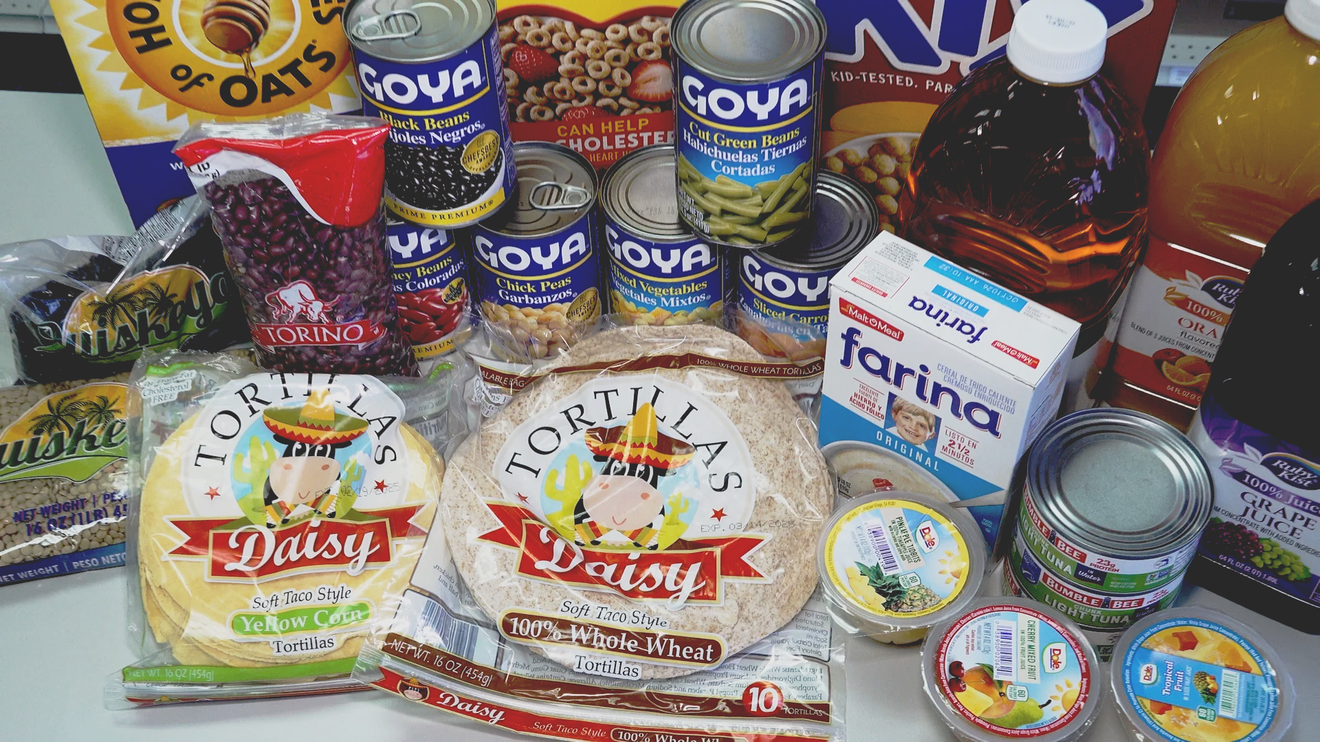 Smiling store employee standing in a grocery aisle with various packaged food items on display.