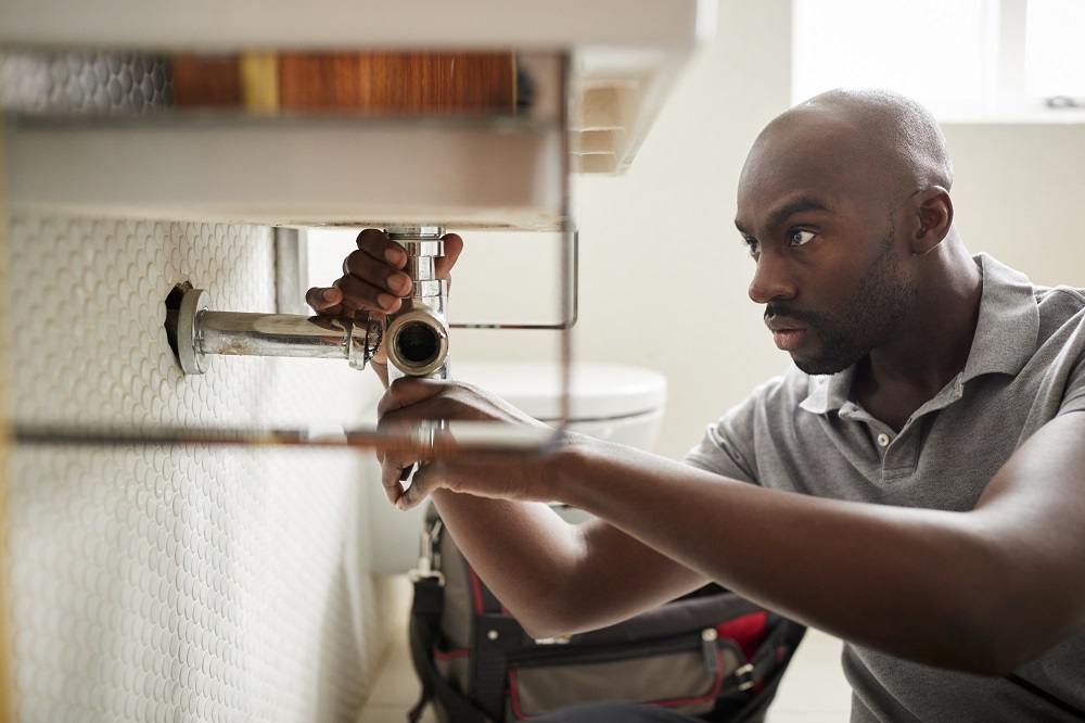 African American Plumber Checking Drain Pipe