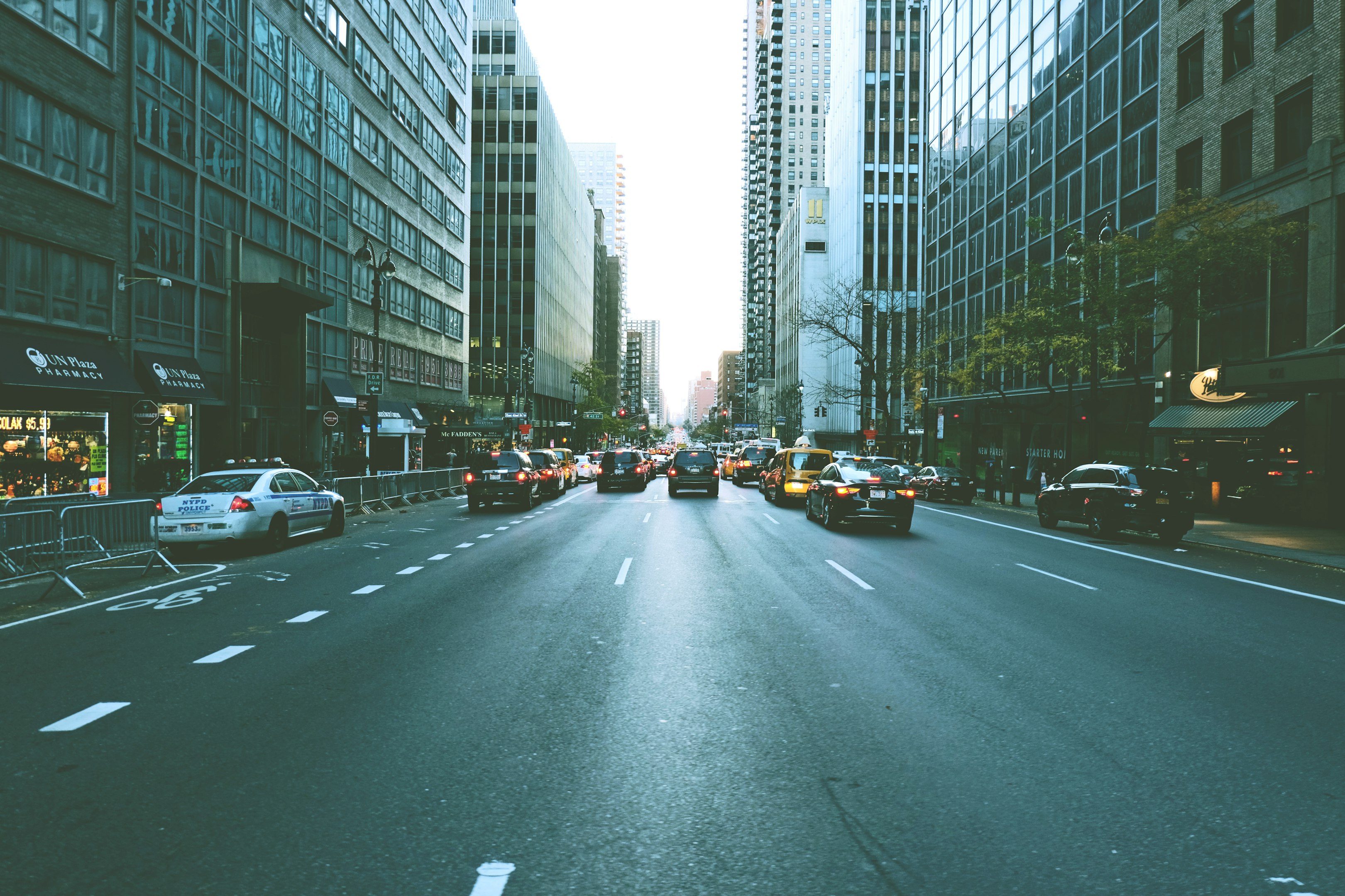 cars on road inline of high rise building during daytime