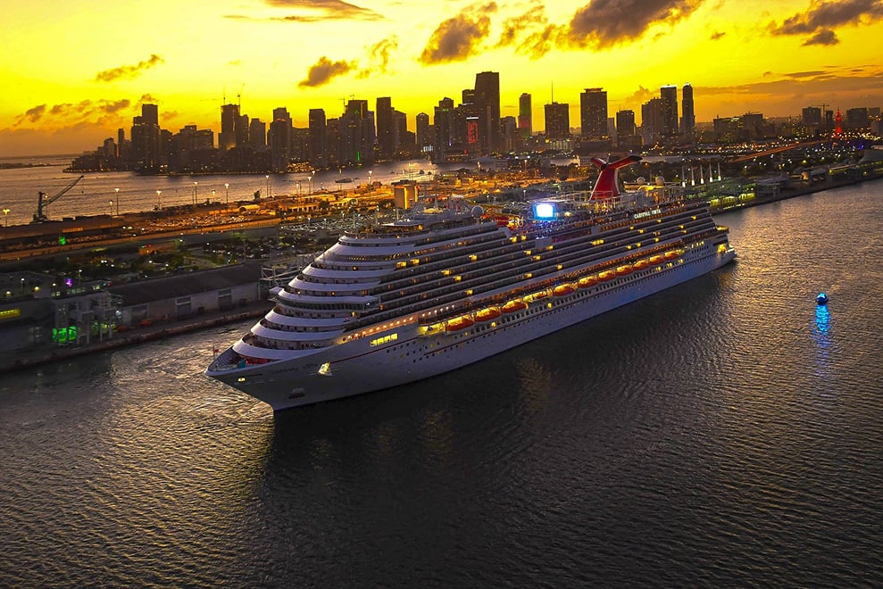 A Carnival cruise ship leaving port at sunset.