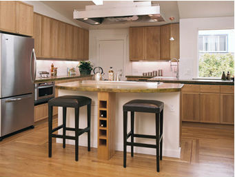 This kitchen features oak cabinets, oak floors, and a concrete island countertop which overhangs to provide bar seating.