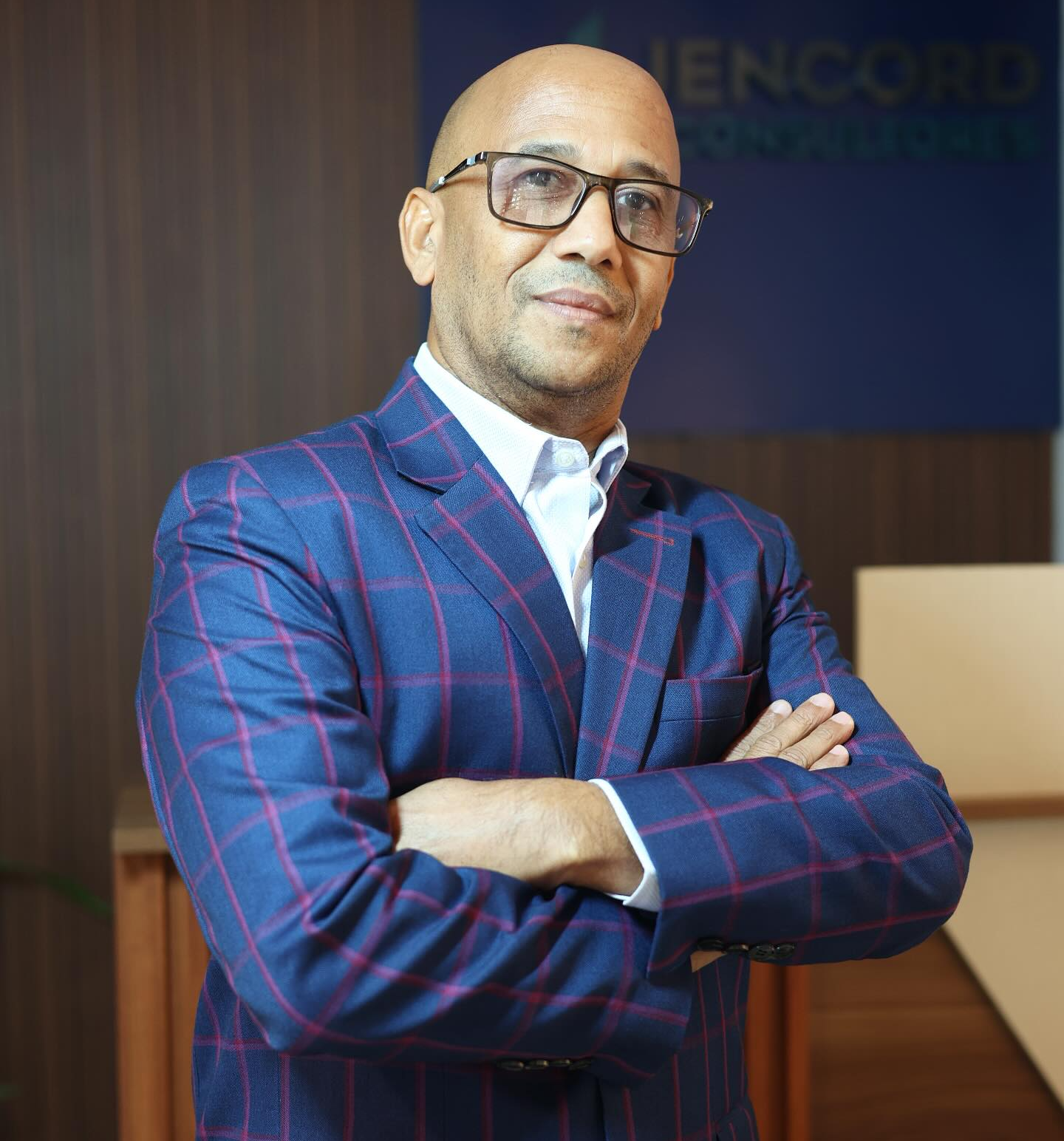 Hombre de negocios analizando datos en pantalla digital dentro de una oficina moderna con colegas al fondo.
