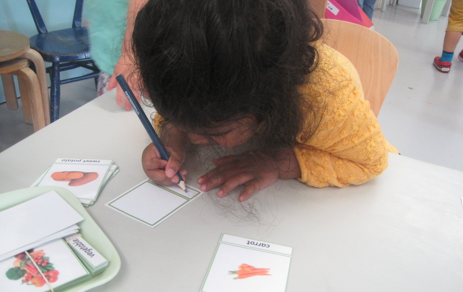 Writing out her own Classified Cards of vegetables.