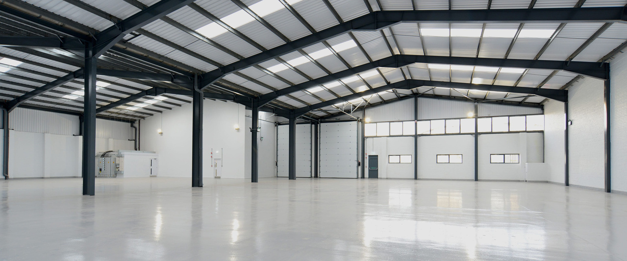 Spacious empty warehouse interior with high ceilings and natural light.