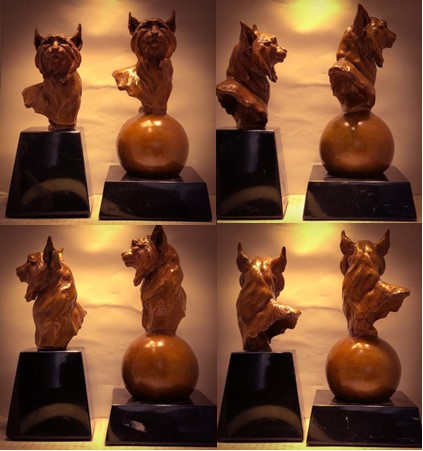 Busto de bronce de mujer con recogido, sobre mesa de mármol, en sala moderna con plantas y sofás.