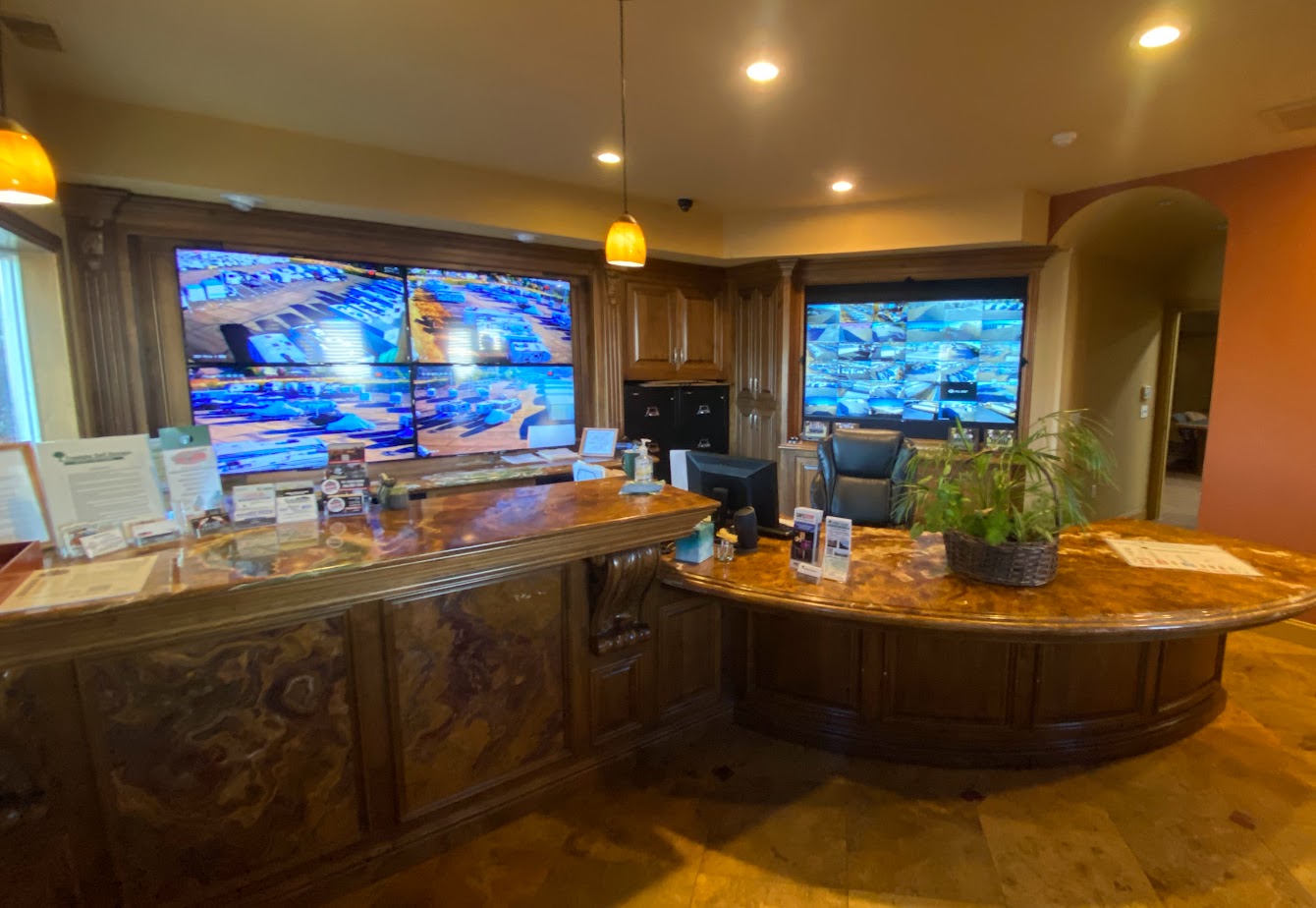 Modern self-storage facility with orange accents, secure gated entry, and parked delivery trucks