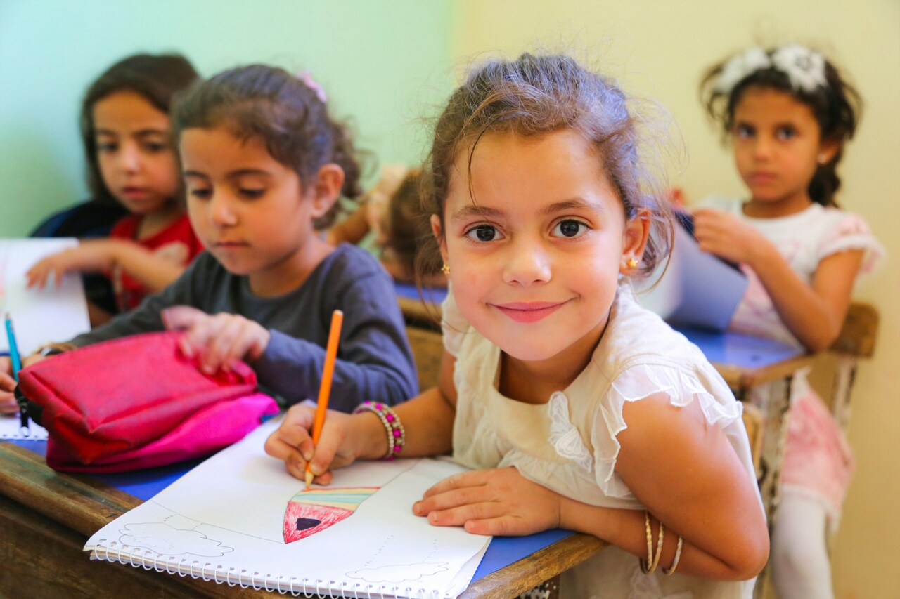 Niñas en un aula dibujando y escribiendo en cuadernos durante una actividad escolar
