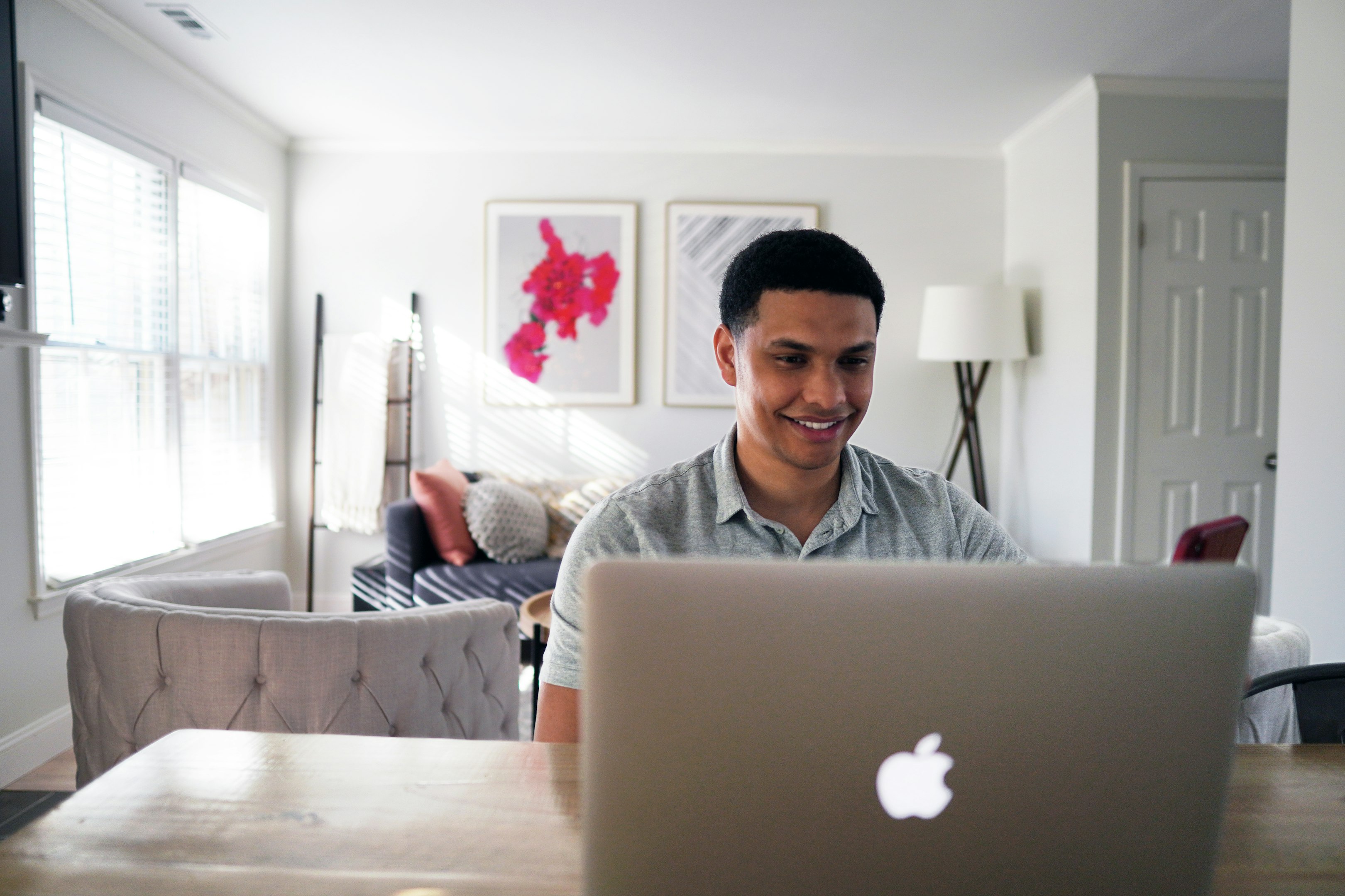 hombre en sudadera gris sentado en una silla frente a un macbook plateado