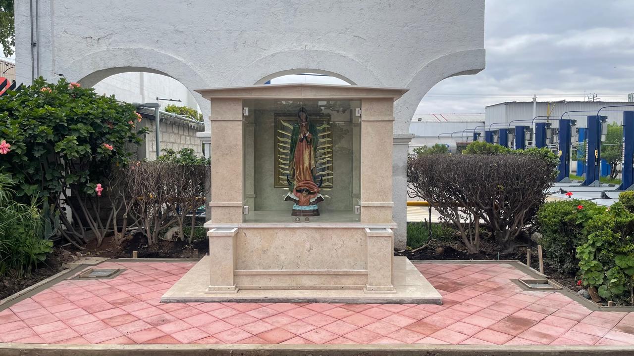 Paisaje urbano moderno con grúas de construcción, edificios de vidrio y árboles bajo un cielo azul con nubes.