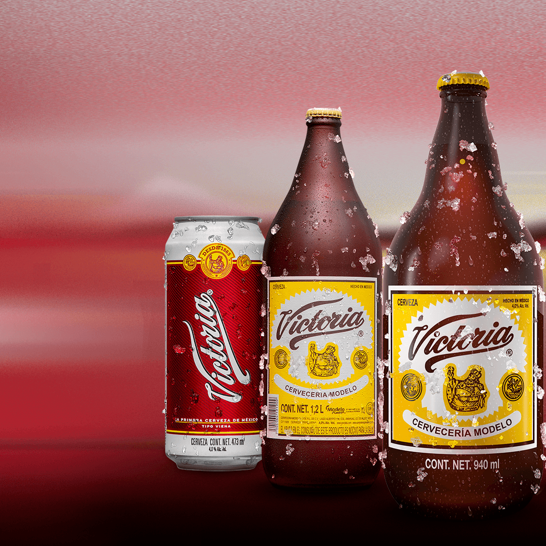 Cerveza Victoria en lata y botellas frías con hielo sobre fondo rojo
