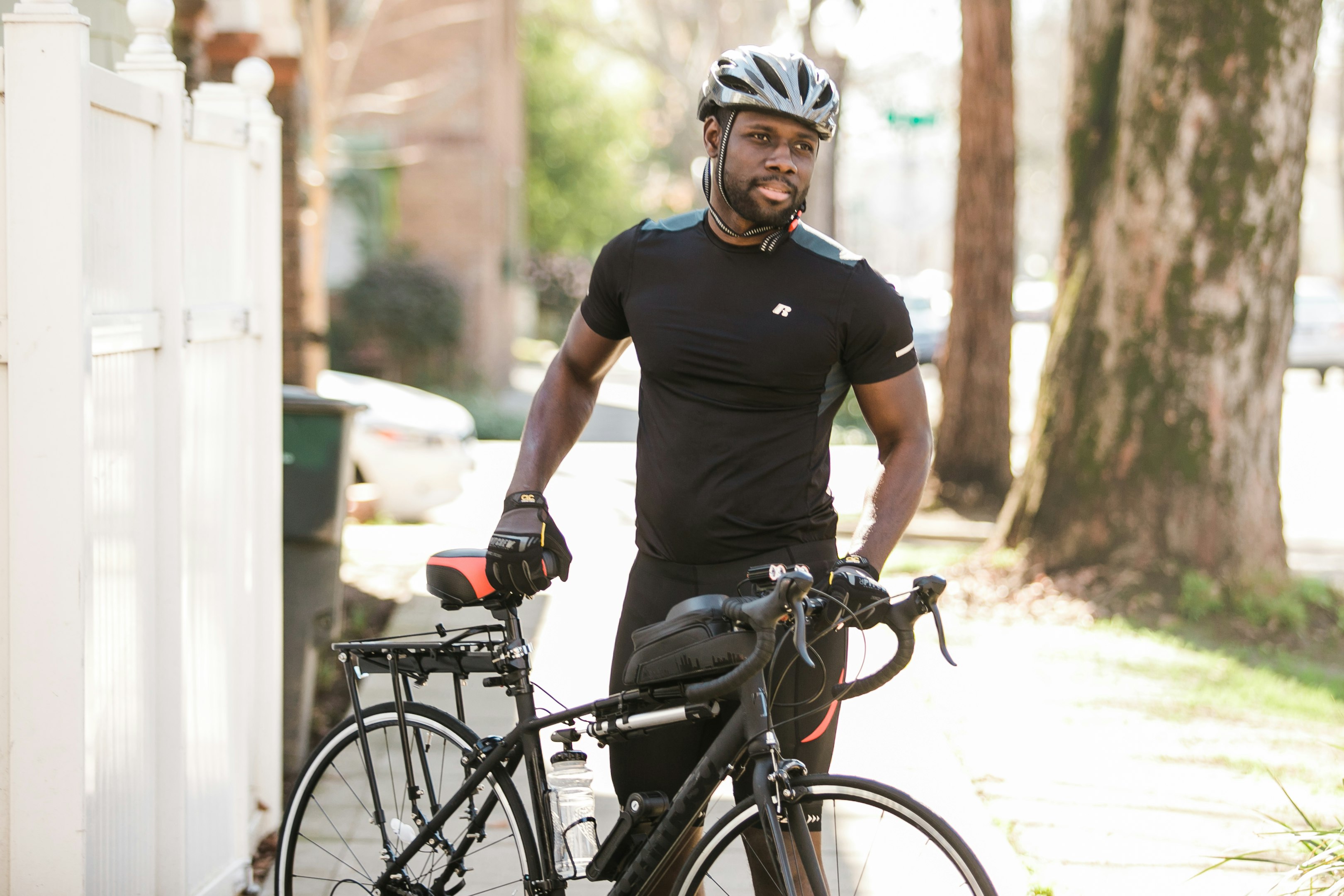 hombre con camiseta negra de cuello redondo y casco blanco montando una bicicleta negra durante el día
