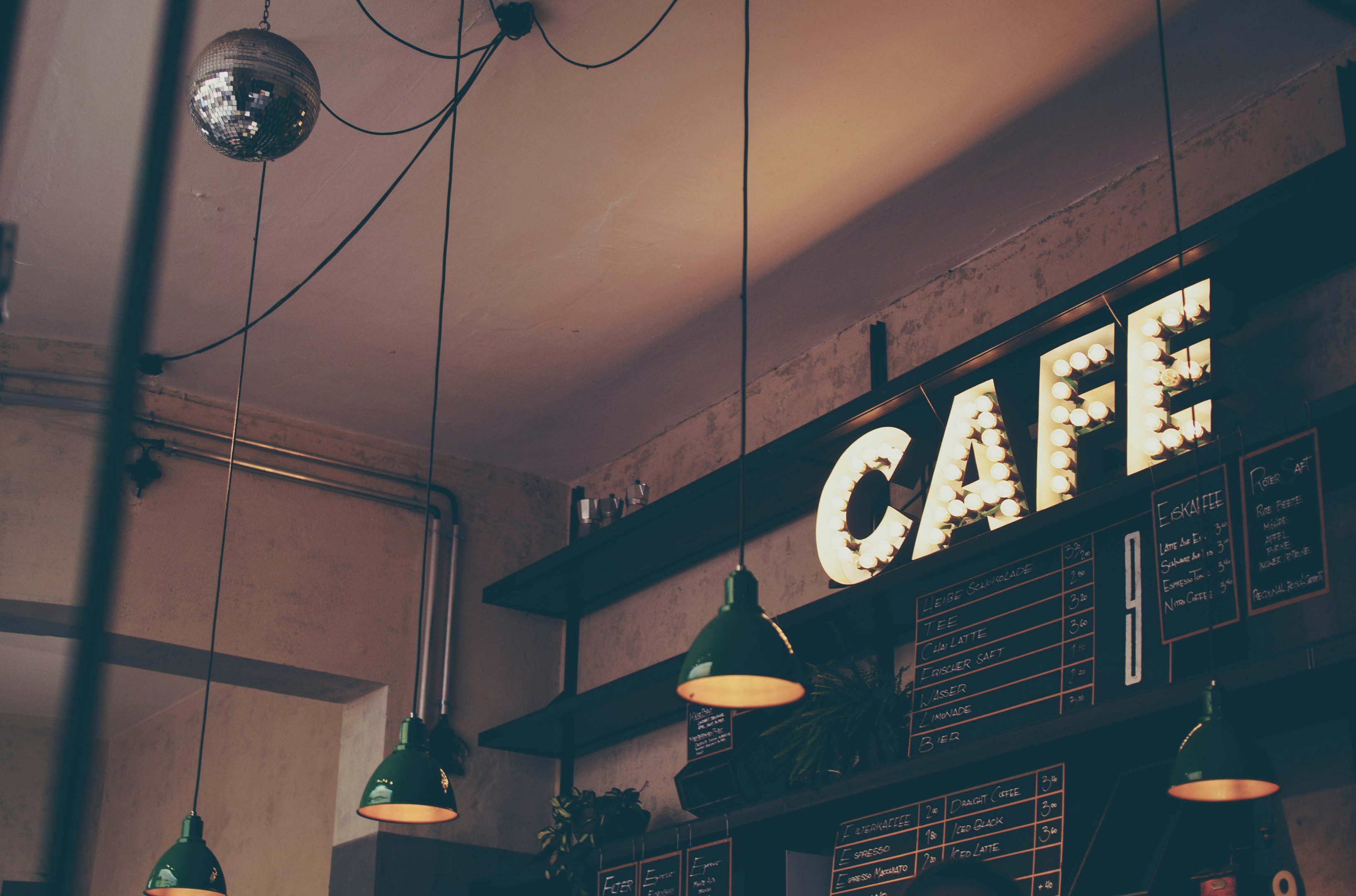 fotografía de café con letrero LED, lámparas colgantes y tableros de menú