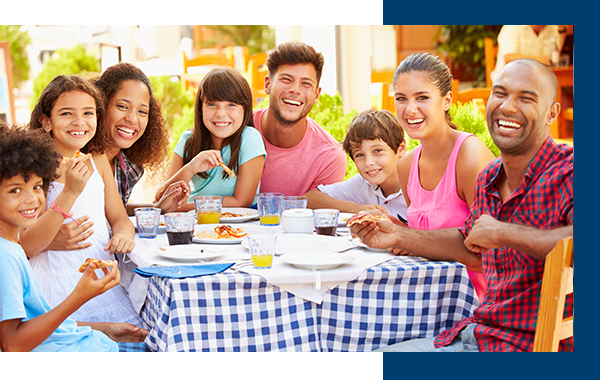 Two Families Eating Meal At Outdoor Restaurant Together