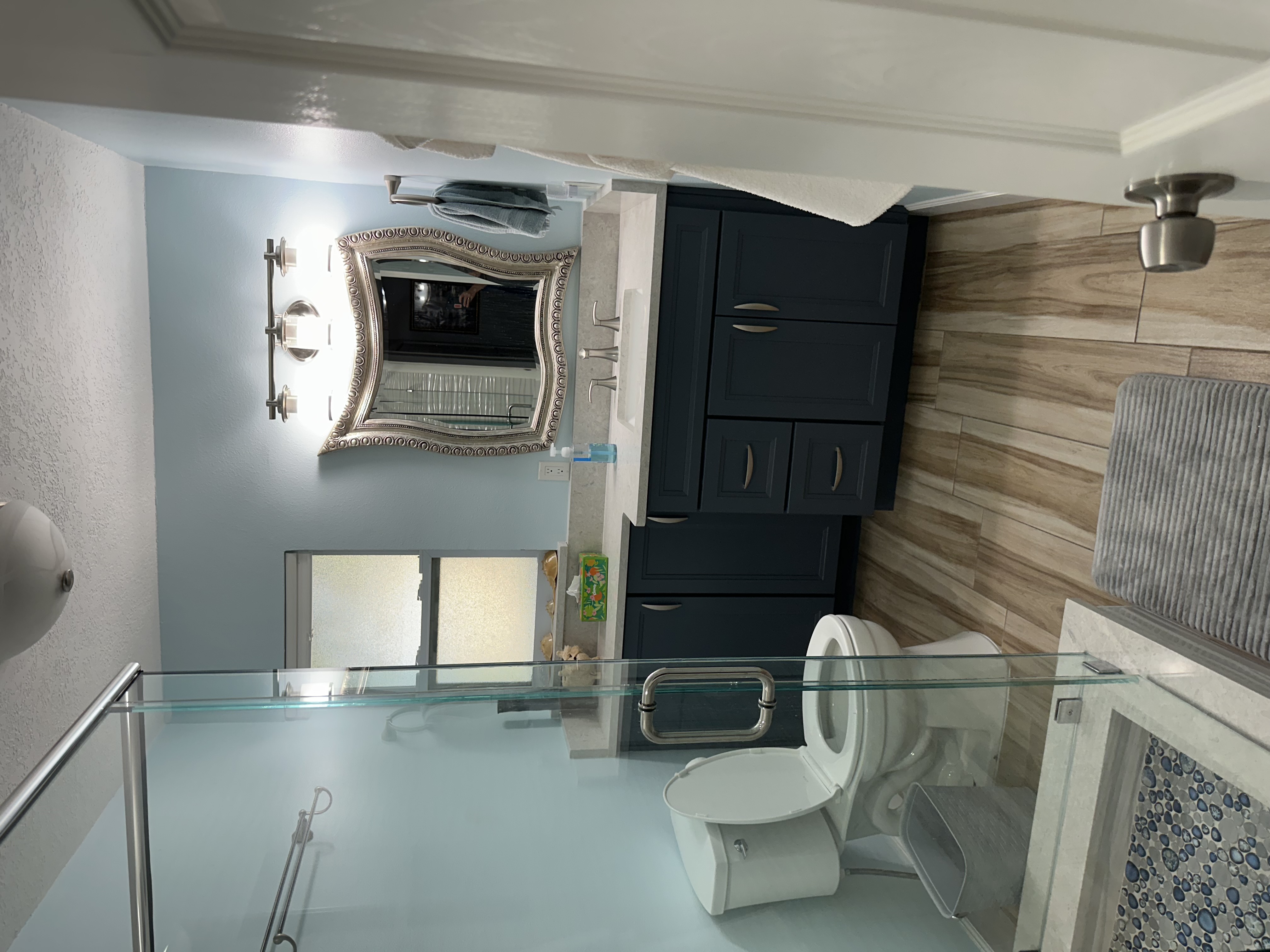Framed by a stylish mirror, this bathroom showcases painted semi-custom cabinetry and a sleek 
Cambria countertop with matching 4" backsplash, with additional storage seamlessly integrated below the window.