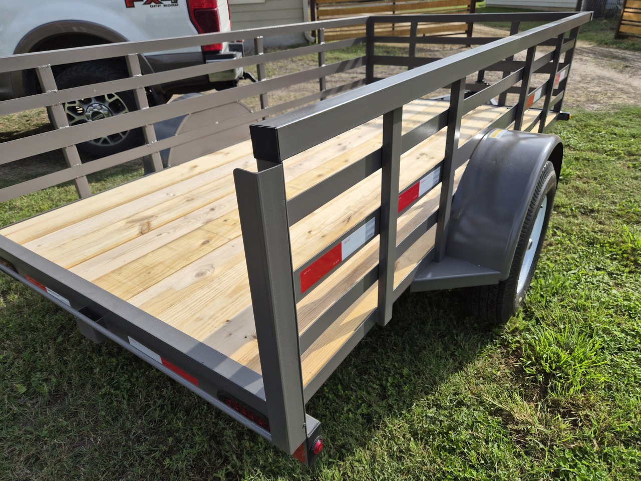 Heavy-duty utility trailer with wooden deck inside a spacious warehouse.