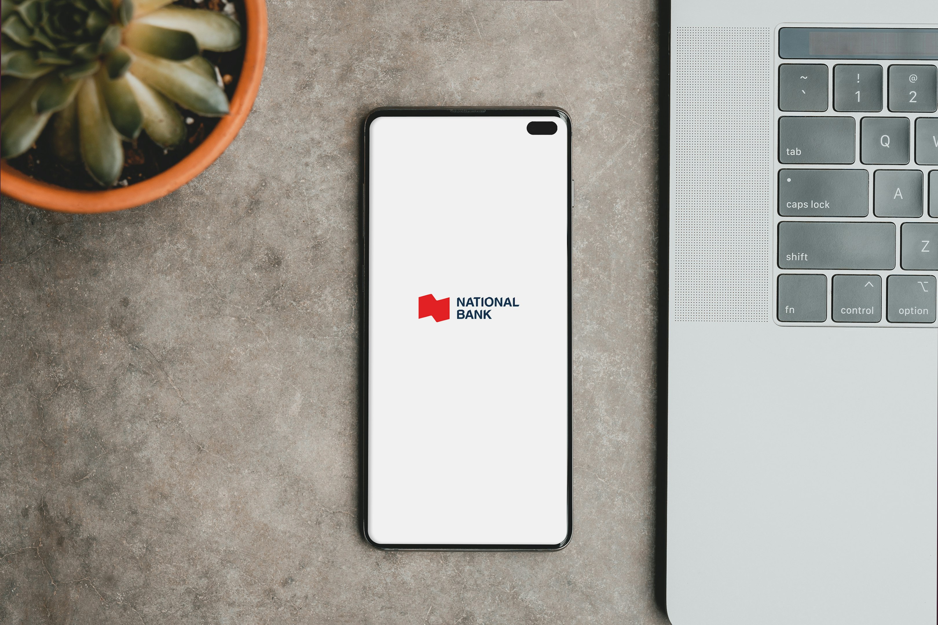 un teléfono celular sobre una mesa al lado de una computadora portátil