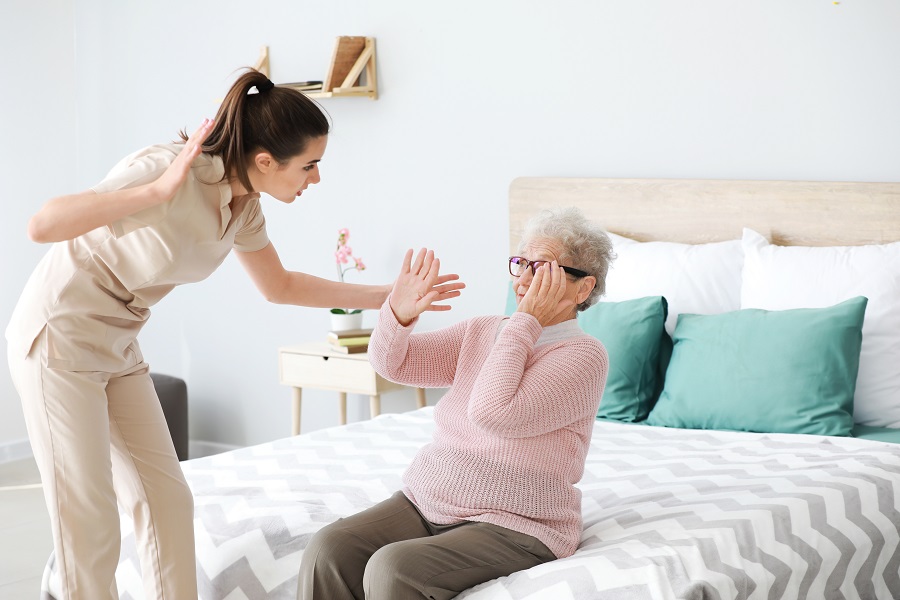 Nurse in Nursing Home Mistreating Elderly Lady Sitting on Bed Nurse in Nursing Home Mistreating Elderly Lady Sitting on Bed