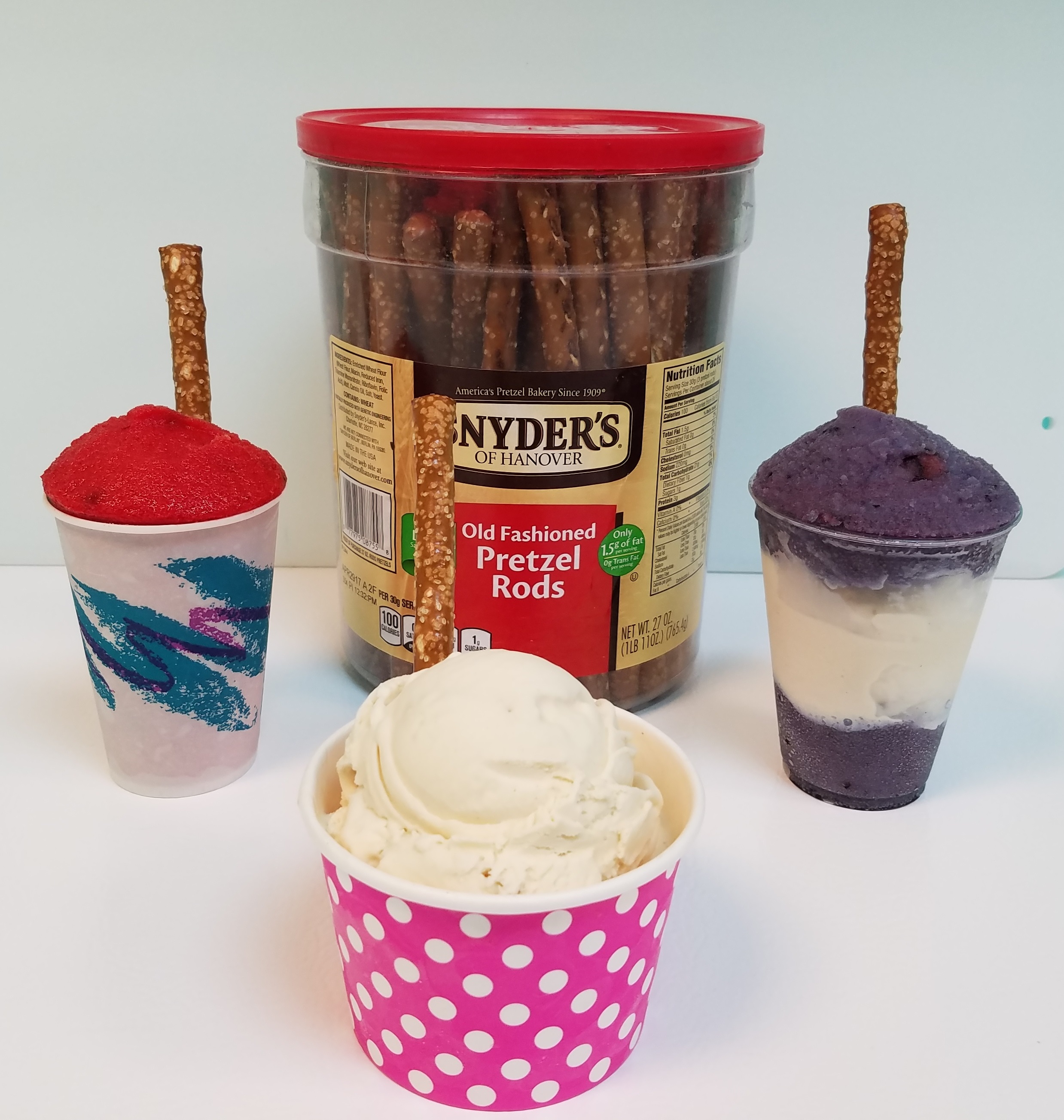 Refreshing dessert with blue slush, vanilla ice cream, gummy worms, and a pretzel stick in a clear cup.