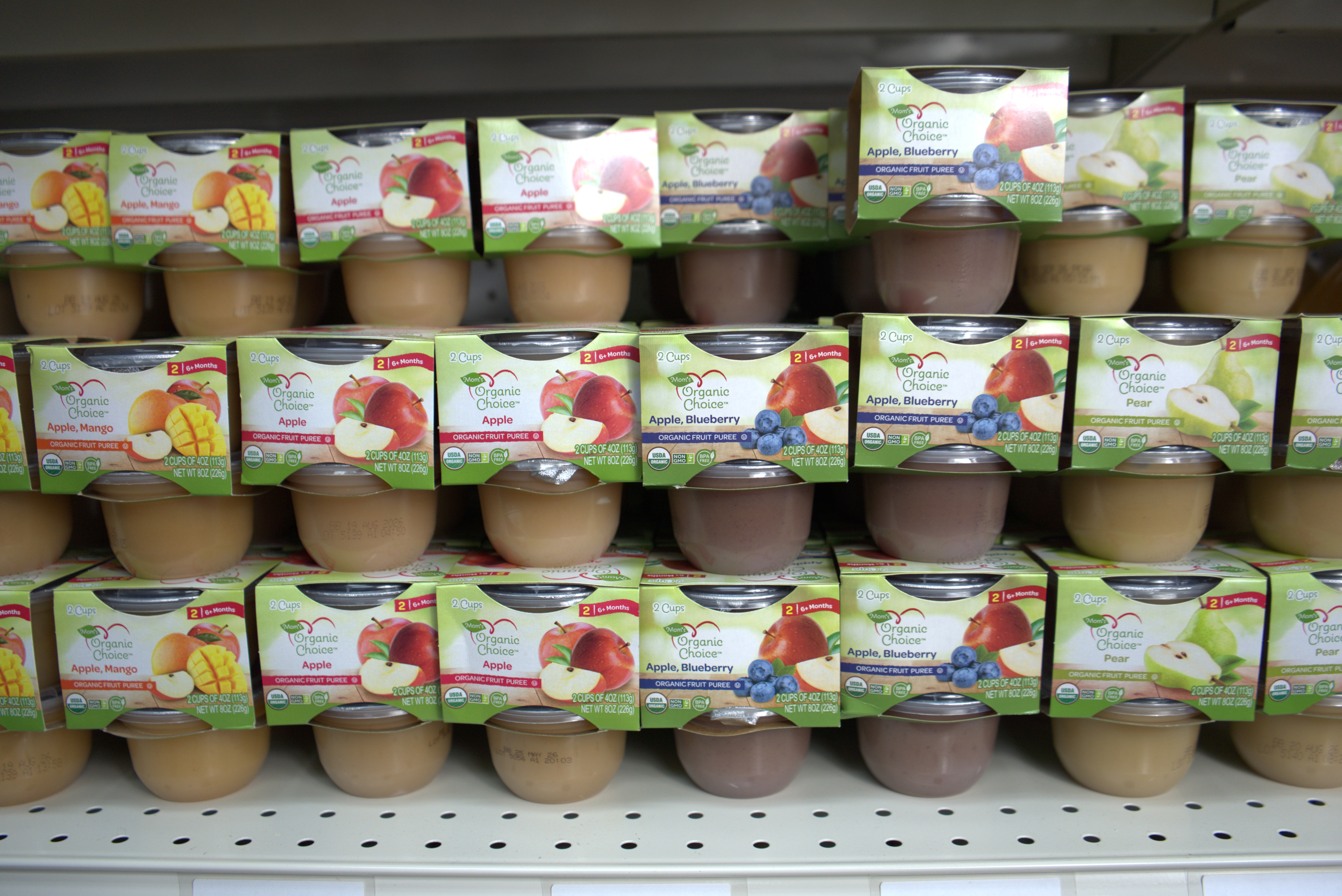 Shopper placing bag of snacks into cart in grocery store aisle