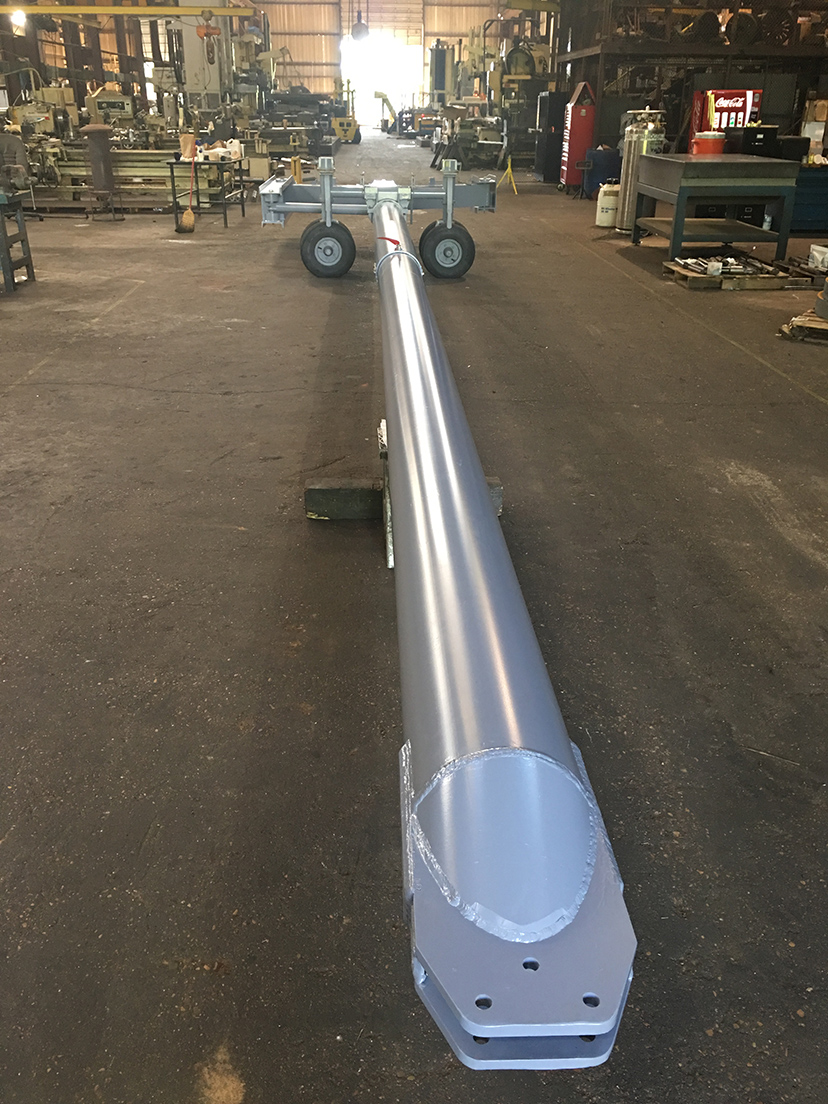 Modern industrial workshop with precision metal components on workbenches, illuminated by overhead fluorescent lighting.