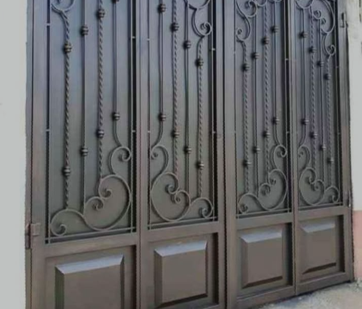 Puerta de hierro forjado con diseño ornamental de patrones curvos y detalles decorativos.