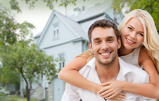 Smiling Couple Hugging Over House Background