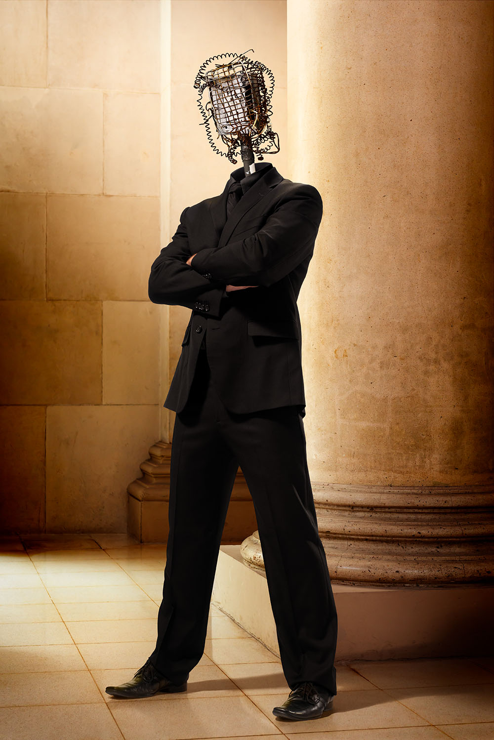 Surreal image of man standing in classical stone building with a head made out of a electrical equipment and wires.